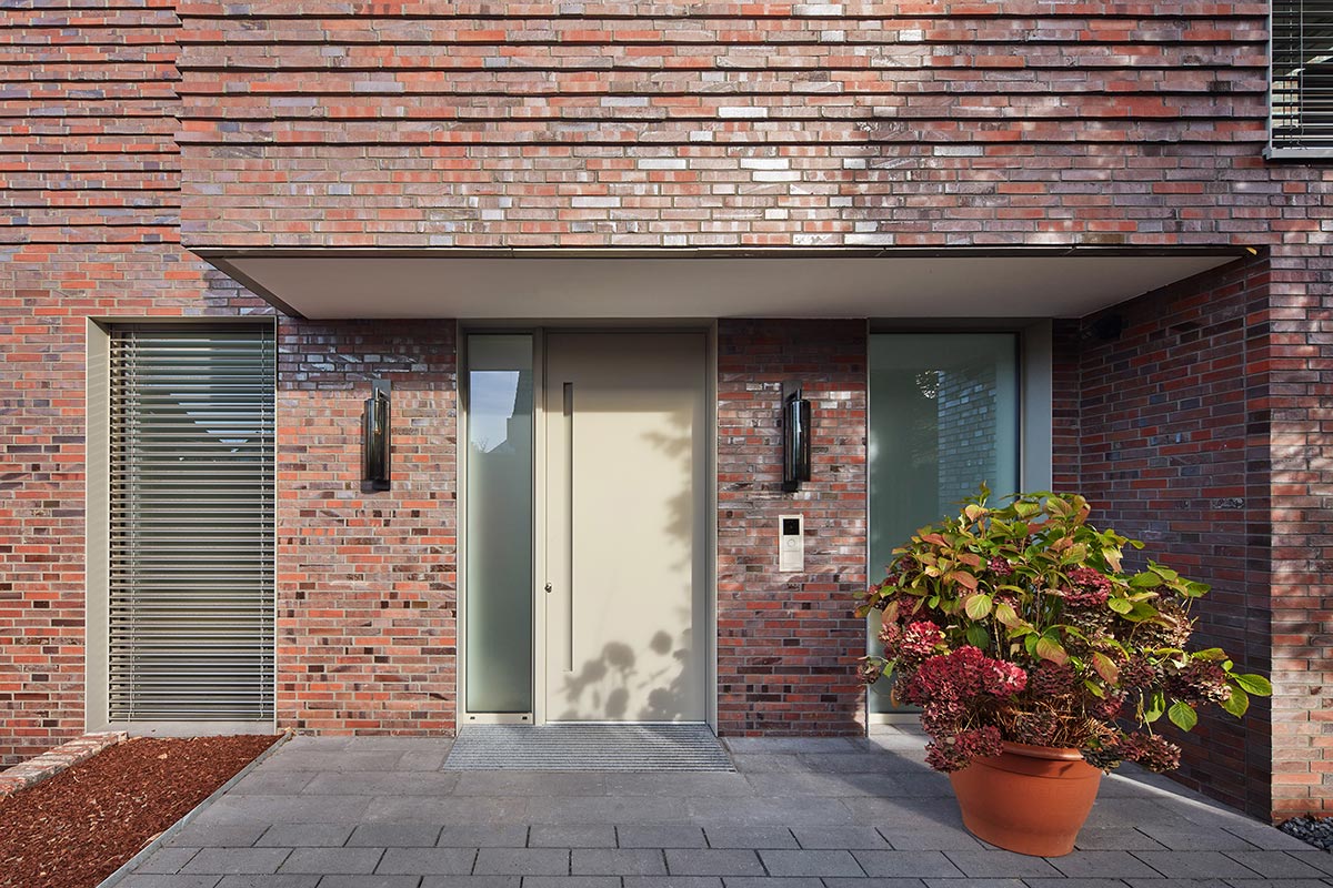 Überdachter Eingangsbereich eines luxuriösen Einfamilienhauses mit einer Hortensie in einem großem Blumenkübel