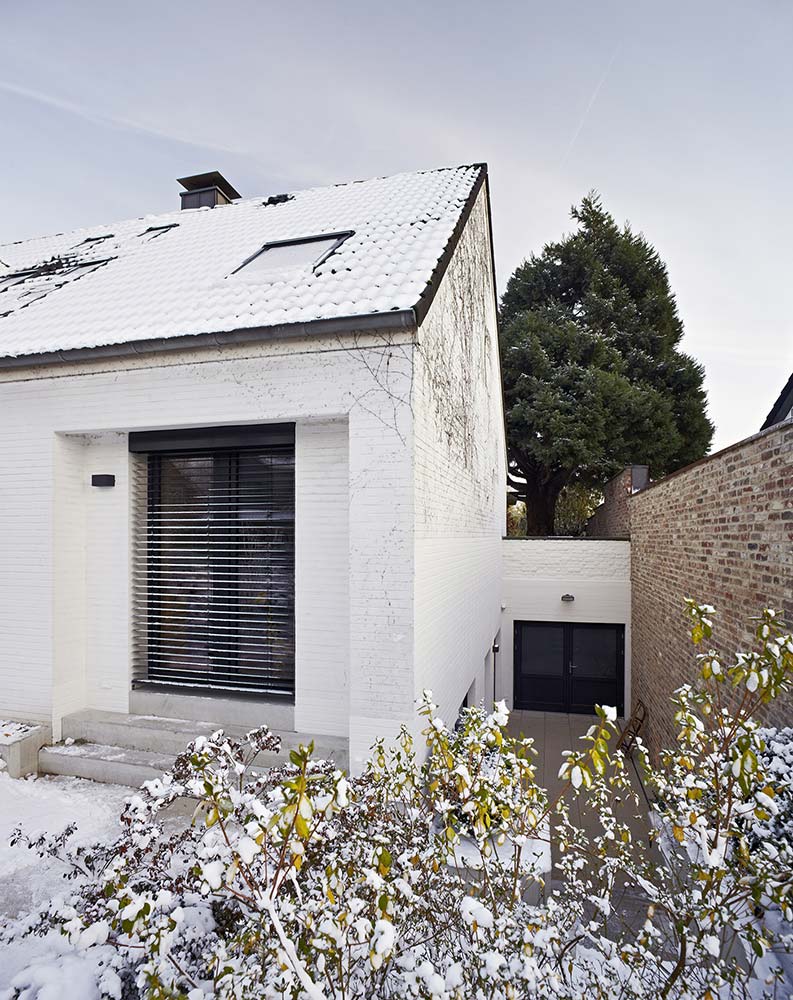 Ein kleiner Spielhof zwischen dem weiß verputzten Haus und einer Backsteinmauer.