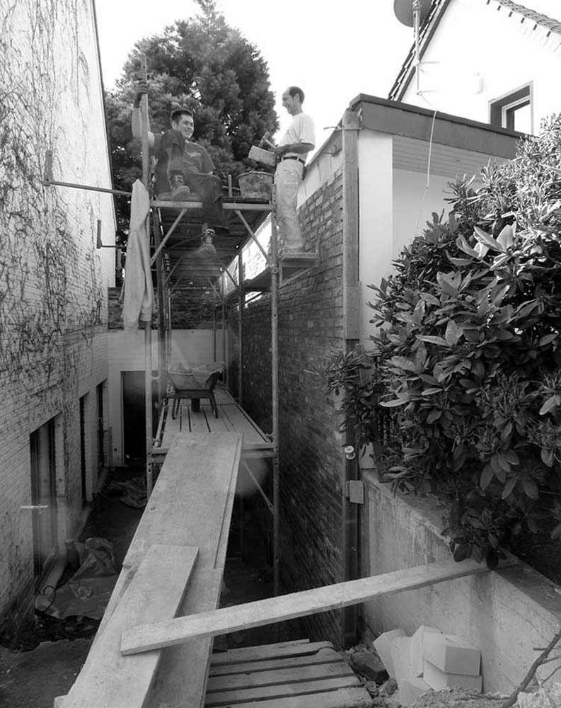 Arbeiter auf einem Baugerüst über einem Hof.