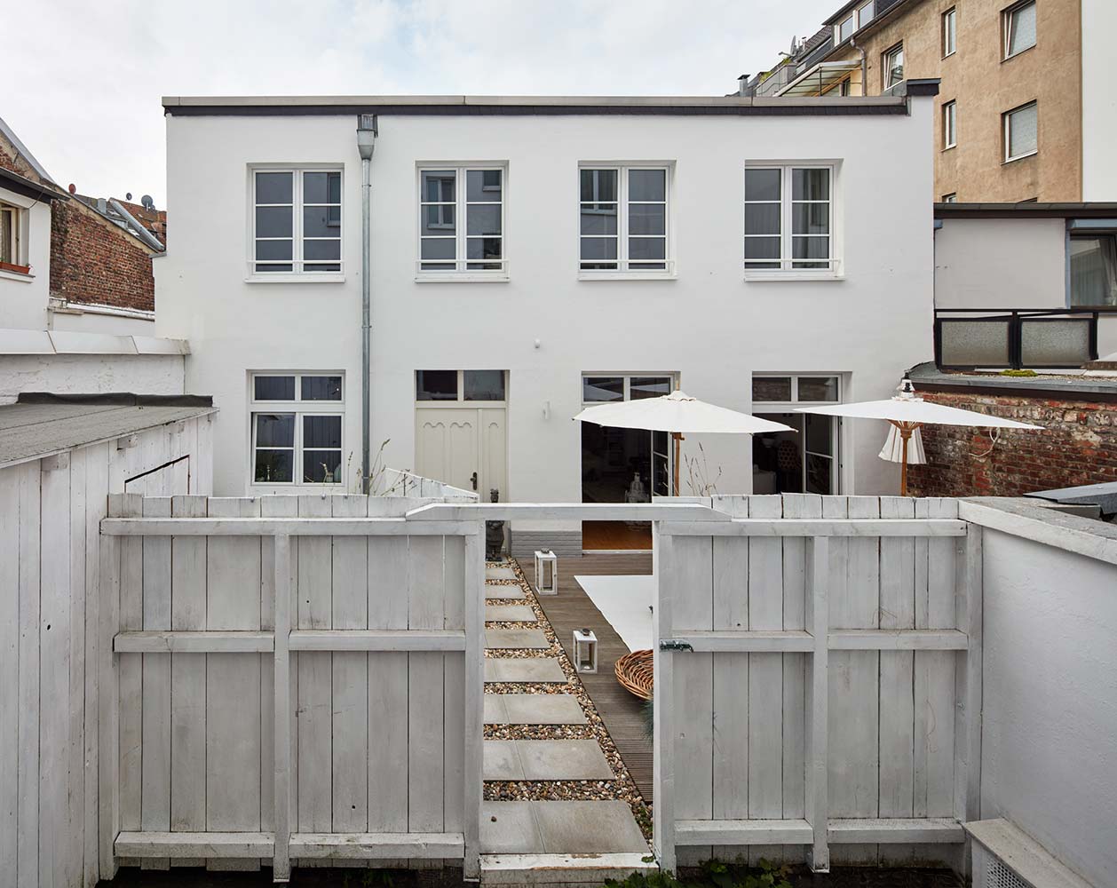 Die Fassade eines Hofgebäudes in Düsseldorf mit neuen Sprossenfenstern und einem Klinkersockel.