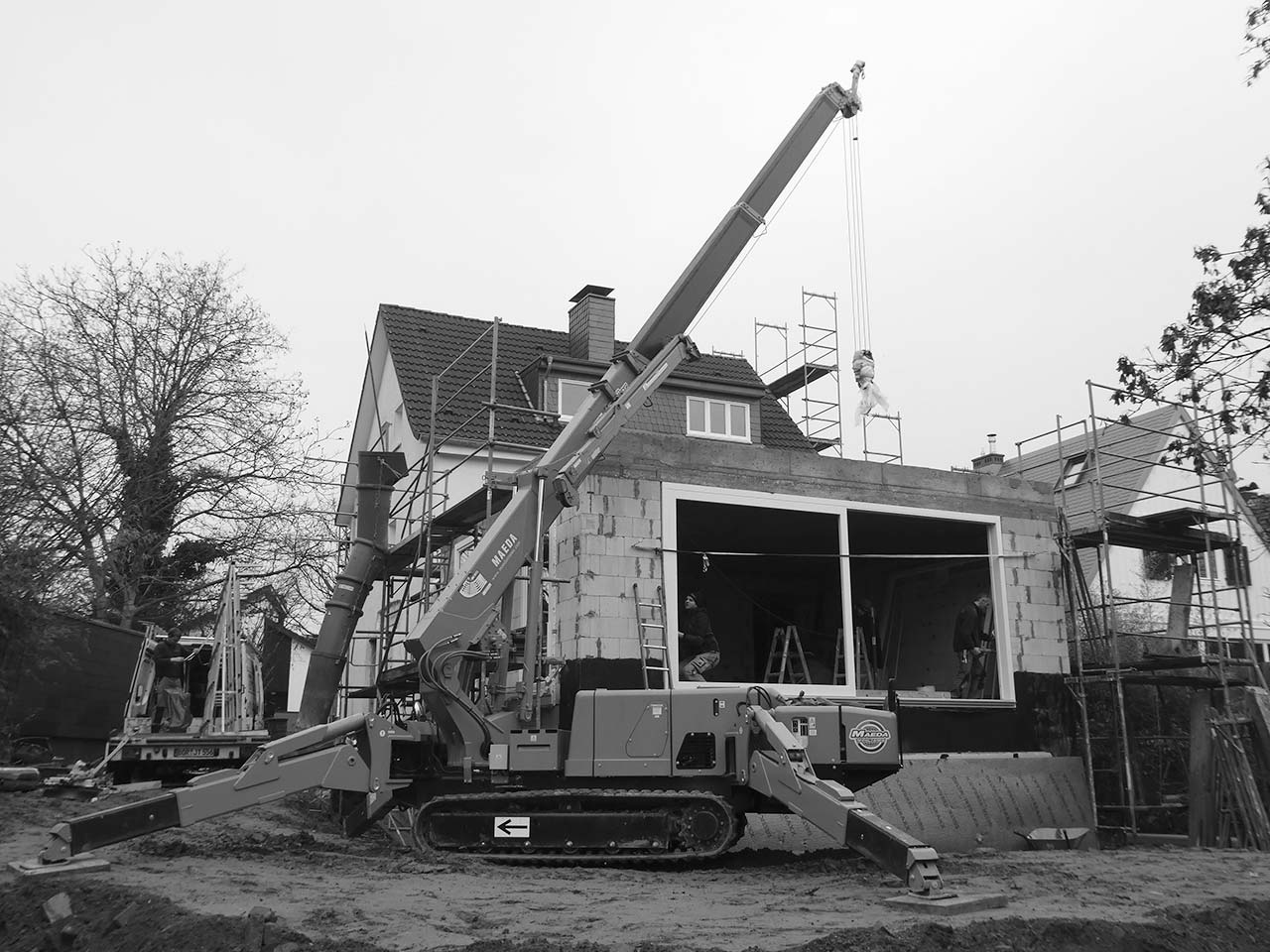 Großes Baufahrzeug vor einer Baustelle mit großem Doppelfenster.