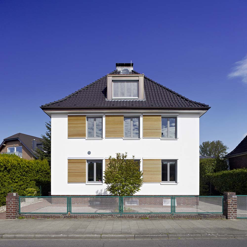 Fassade eines modernisierten und umgebauten Zweifamilienhauses mit geöffneten Schiebe-Fensterläden.