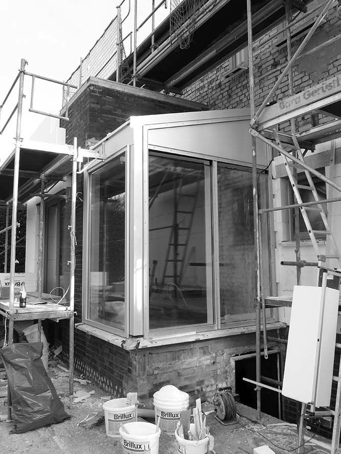 Bauarbeiten an einem alten Zweifamilienhaus mit Gerüst und verschiedenen Baumaterialien.