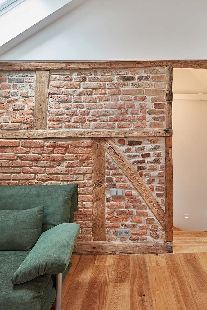 Restaurierte Fachwerkwand mit Backsteinfüllungen, davor ein neuer Holzdielenboden.