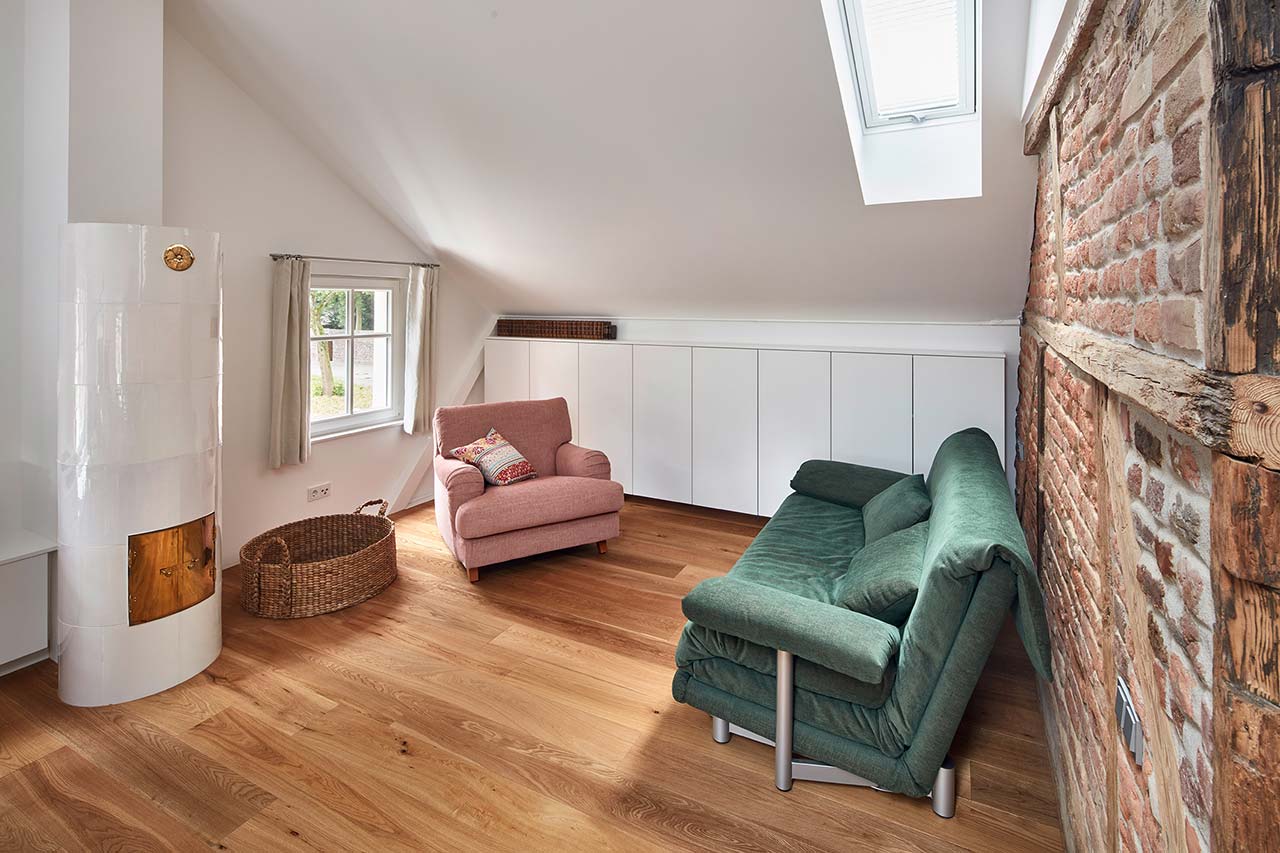 Wohnzimmer mit Backsteingefüllter Fachwerkwand, belichteter Dachschräge und Einbauschränken.