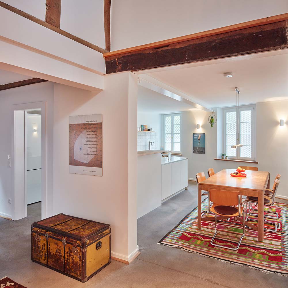 Essplatz mit offener Küche, davor die Eingangshalle mit Luftraum in das Obergeschoss.