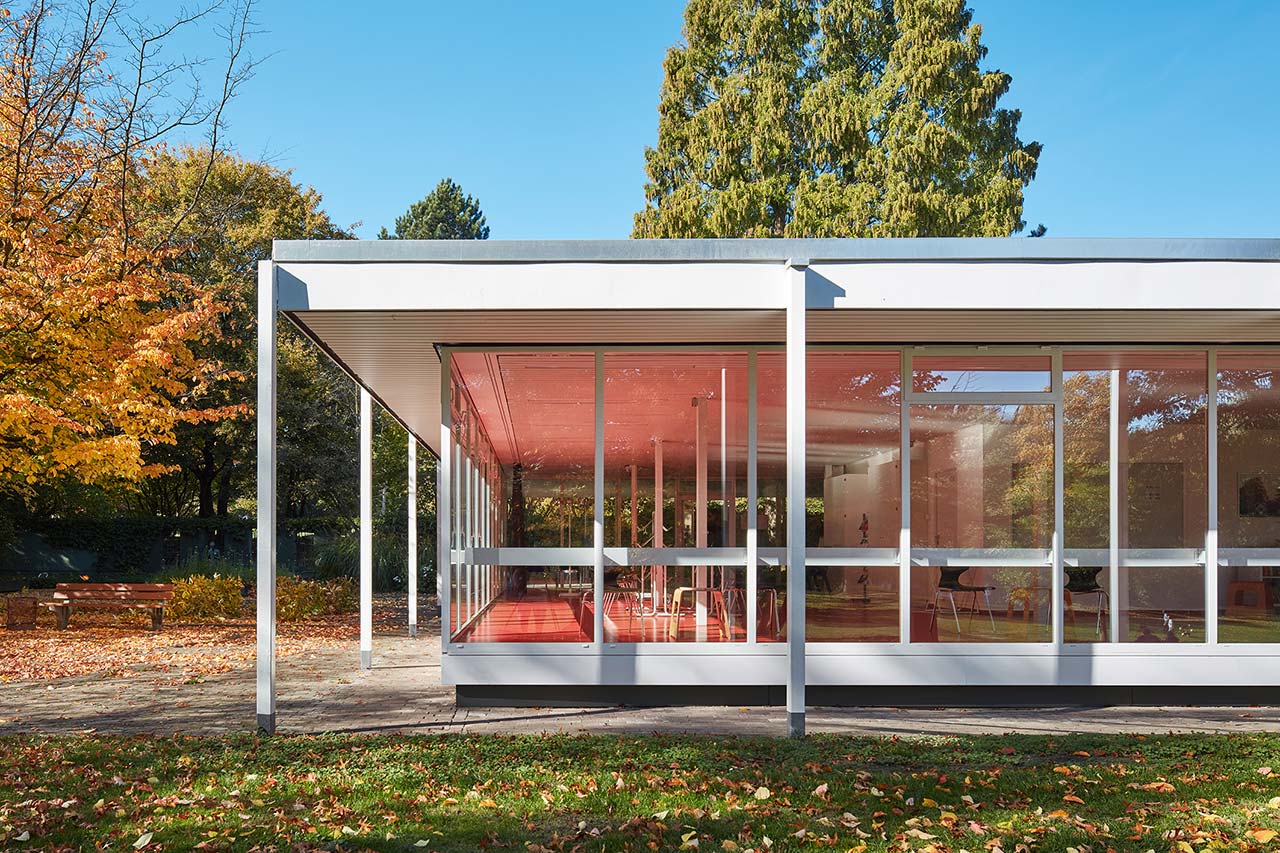 Gläserner Pavillon mit umlaufendem Dachvorsprung.