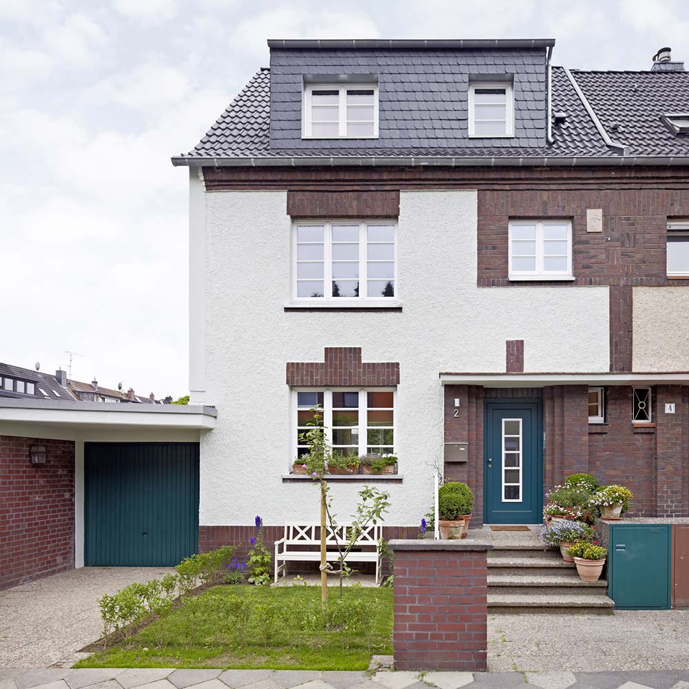 Fassade des Reihenendhauses aus dem jahre 1929 mit Backsteinelementen und grüner Haustüre.