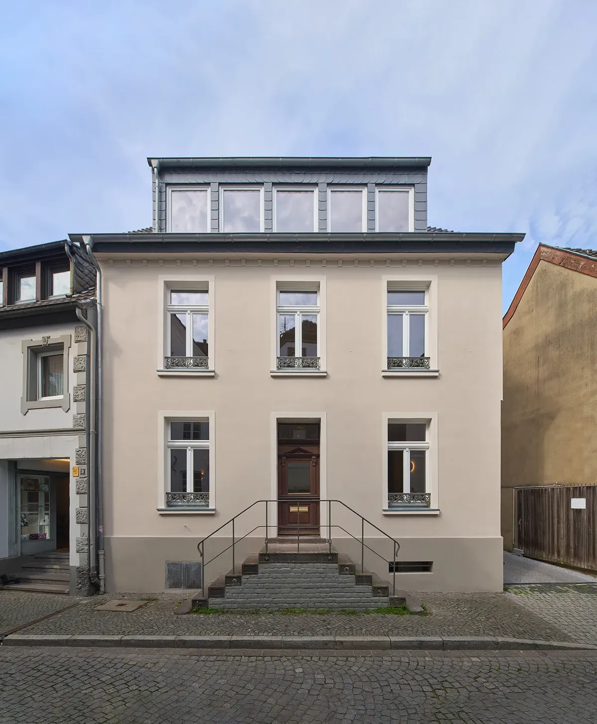 Wohnraum einer modernisierten Maisonettewohnung mit offener Galerie, Eichenparkett im Fischgrätmuster, integrierter Bücherwand und Zugang zur verglasten Terrasse.