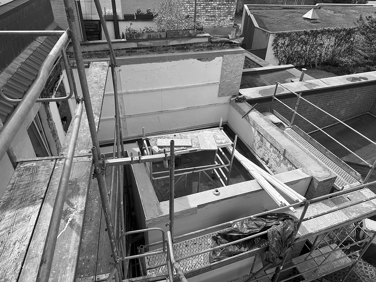 Blick auf den rückwärtigen Gebäudeteil während der Sanierung mit Gerüst, geöffneten Dach- und Wandbereichen sowie angrenzenden Nachbargebäuden.