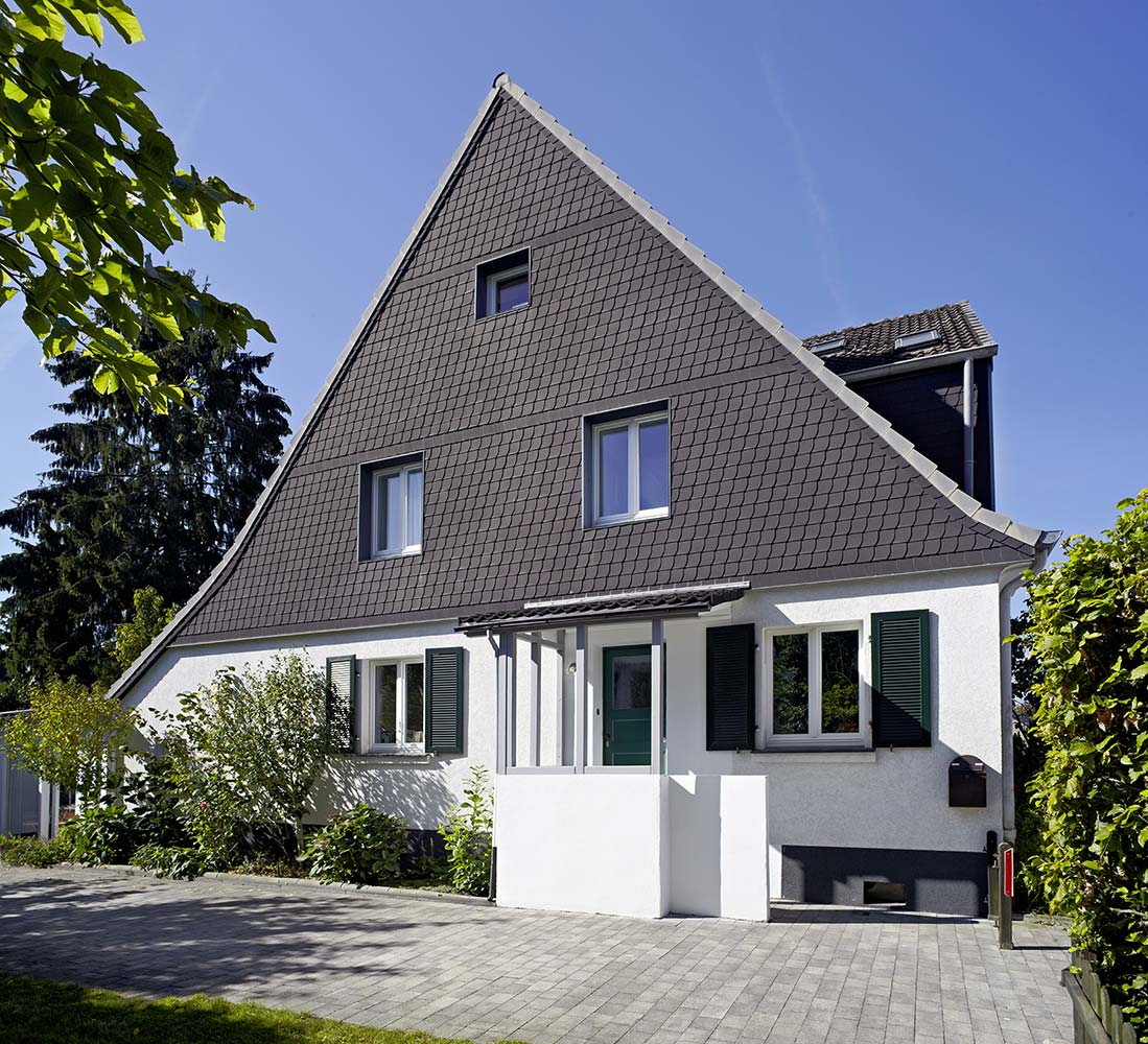 Fassade einer sanierten Doppelhaushälfte mit Schiefergiebel und Klappfensterläden.