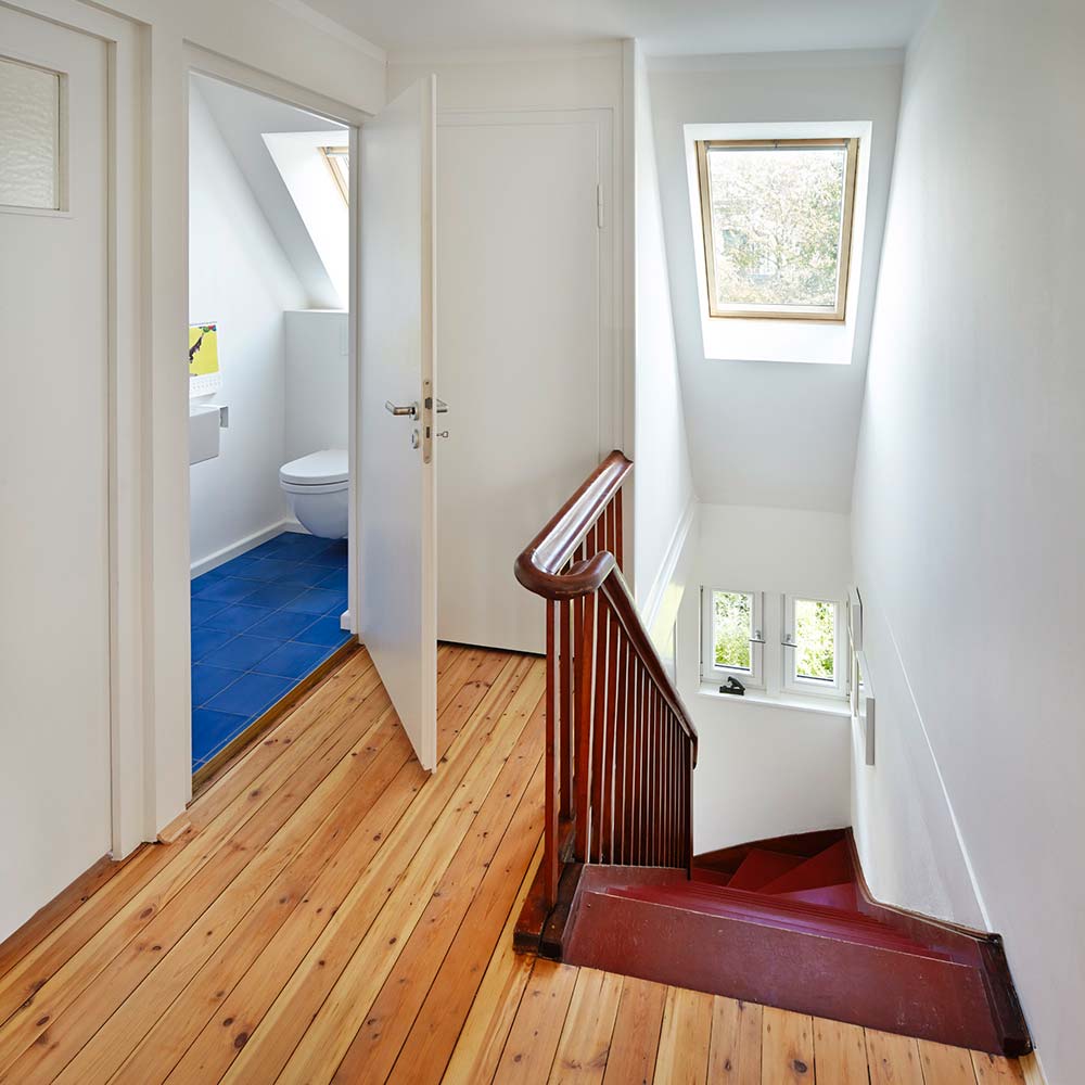 Blick in das Treppenhaus mit aufgearbeitetem Holzdielenboden und neuen Dachfenstern.